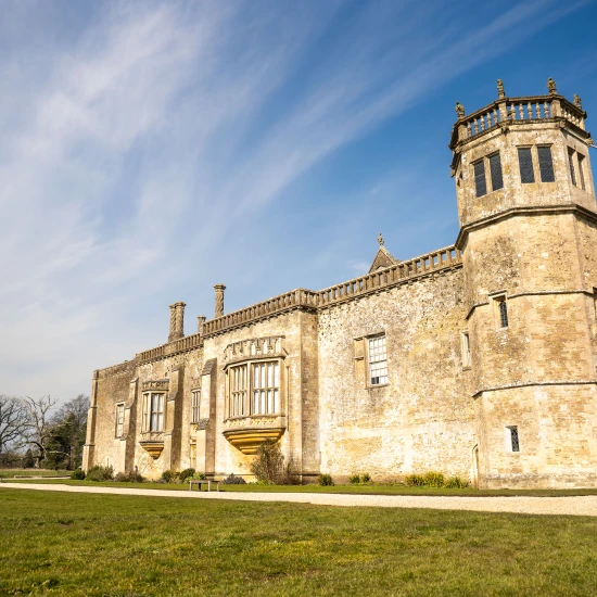 A historic stone building with a tower, set against a clear blue sky and surrounded by lush green grass.
