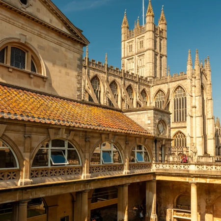 Stunning architectural view of Bath's historic buildings under a clear blue sky, showcasing intricate stonework and rooftops.