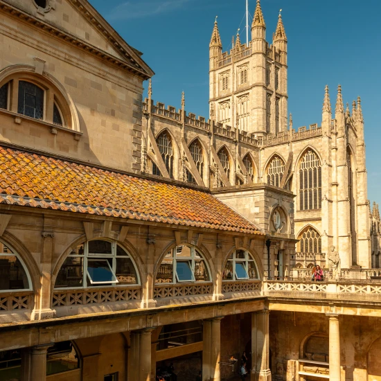 Stunning architectural view of Bath's historic buildings under a clear blue sky, showcasing intricate stonework and rooftops.