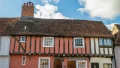 Historic timber-framed houses with colorful facades under a blue sky, typical of charming UK architecture.