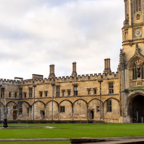 Historic architecture featuring a clock tower and arched columns, set in a green courtyard with a fountain. Perfect for tours.