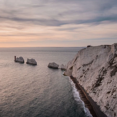 Stunning coastal view of white cliffs, rocky outcrops, and a serene ocean at sunset, showcasing the beauty of the UK.