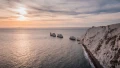 Stunning coastal view of white cliffs, rocky outcrops, and a serene ocean at sunset, showcasing the beauty of the UK.