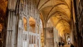 Interior of a grand cathedral featuring intricate architecture, tall arches, and visitors exploring the historic space.