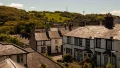 View of quaint houses with slate roofs nestled in lush green hills under a clear sky, showcasing the charm of UK landscapes.