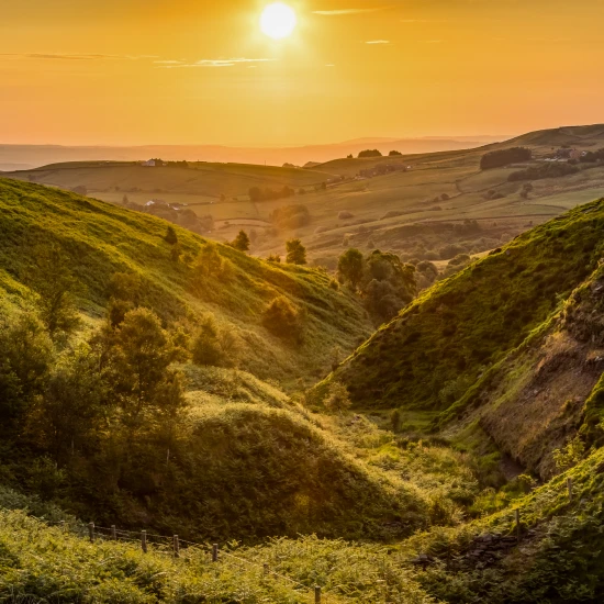 A tranquil sunset over rolling green hills, showcasing the natural beauty of the UK countryside, ideal for small group tours.