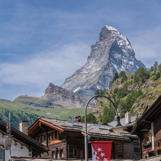 Scenic view of alpine houses with a backdrop of the iconic snow-capped mountain against a clear blue sky.