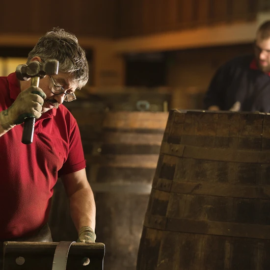 Craftsmen meticulously constructing wooden barrels in a workshop, showcasing traditional craftsmanship in action.