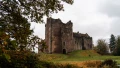 A historic castle set on a grassy hill, surrounded by trees under a cloudy sky, evoking a sense of adventure and history.
