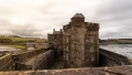 Historic stone castle overlooking a river and lush green landscape under a cloudy sky, showcasing the beauty of UK heritage.
