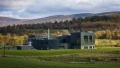 Modern building surrounded by green fields and rolling hills under a cloudy sky, capturing the beauty of the UK landscape.