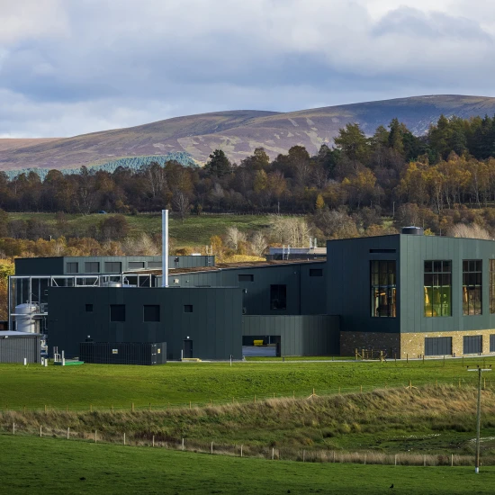 Modern building surrounded by green fields and rolling hills under a cloudy sky, capturing the beauty of the UK landscape.