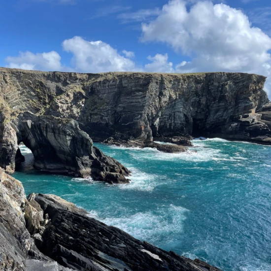 blue waves crashing into the rocky cliff face