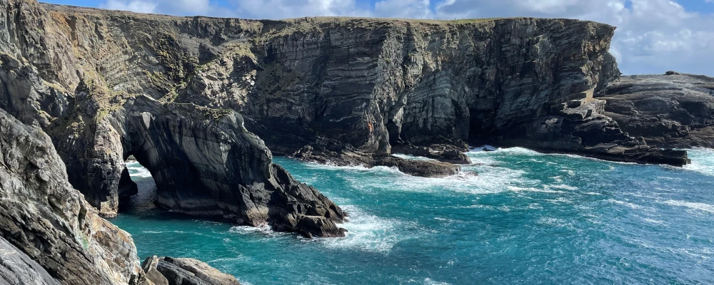 blue waves crashing into the rocky cliff face