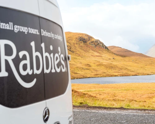 Rabbie's bus with Scottish Highland mountains