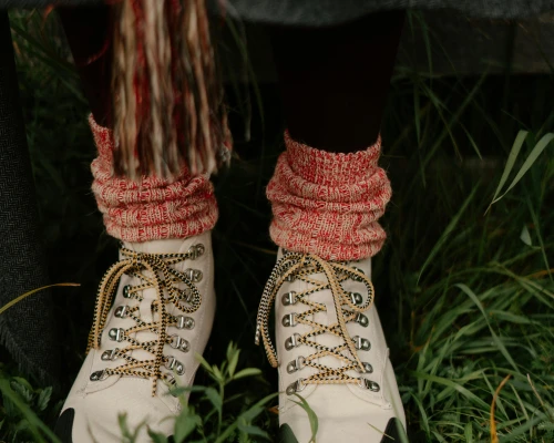 A close-up of white hiking boots with colorful knitted socks, set against a grassy background, conveying outdoor adventure vibes.