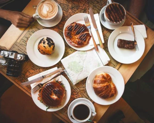 A table spread with coffee, pastries, and a map, suggesting a cozy break during a small group tour in the UK.