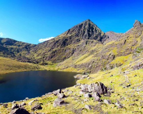 Stunning landscape of rugged mountains surrounding a serene lake under a clear blue sky in the UK. Ideal for small group tours.