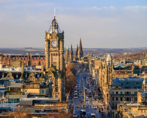 Panoramic view of Edinburgh showcasing the iconic clock tower and historic buildings along a bustling street.