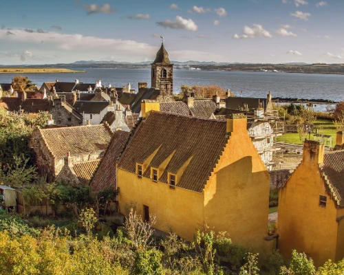 Charming seaside village with colorful houses, a historic clock tower, and scenic views of the water and surrounding landscape.