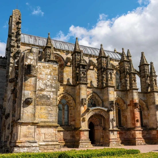 Stunning view of a historic stone church with intricate architecture under a blue sky with scattered clouds.
